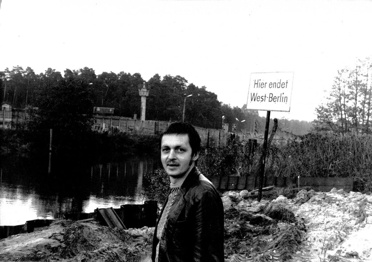 default-422 A man stands in front of the Spree river in black and white, with the Berlin wall behind him.