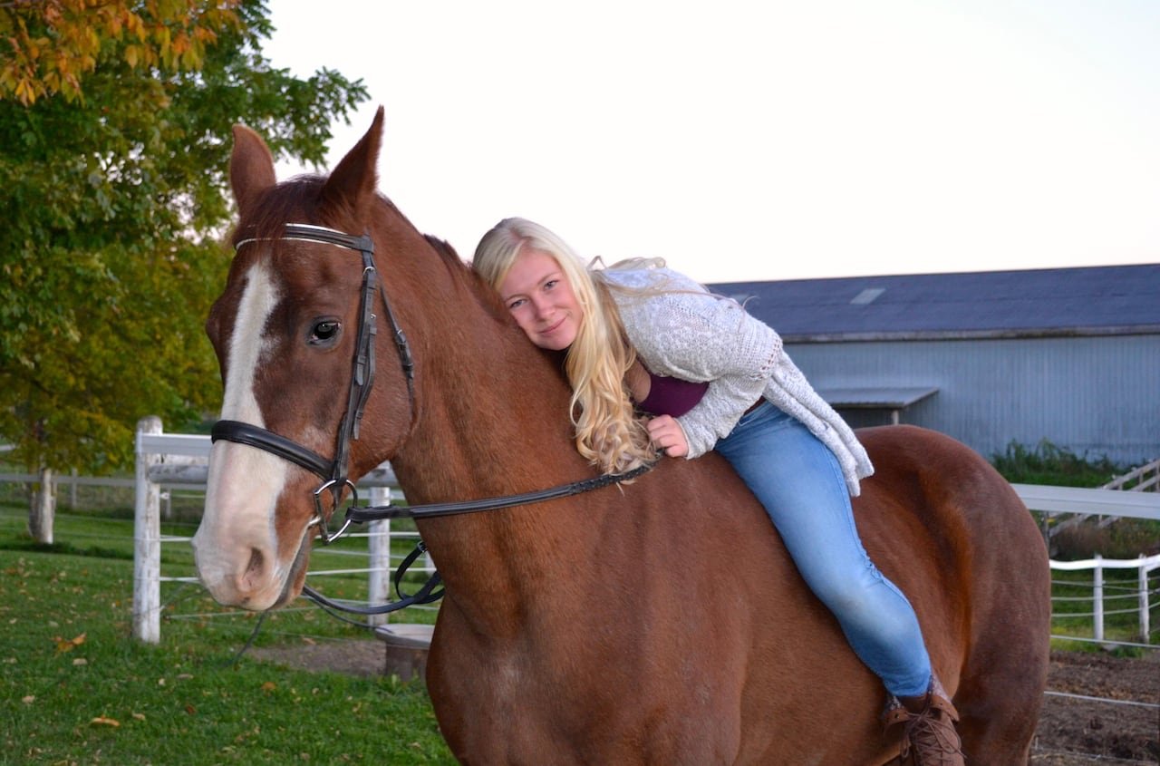 default-88 A woman sitting bareback on a horse bends down to hug it.