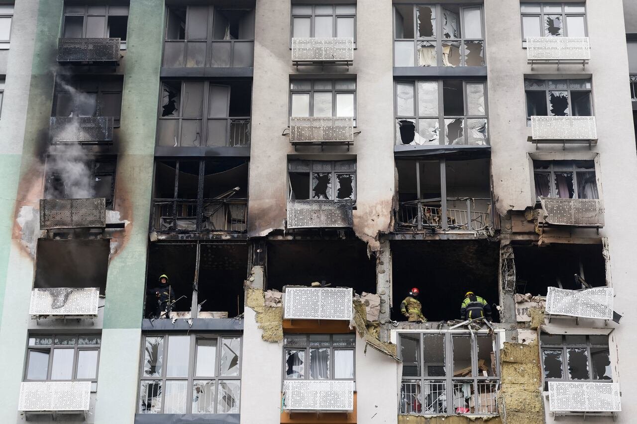 Firefighters work at the site of a damaged apartment building.